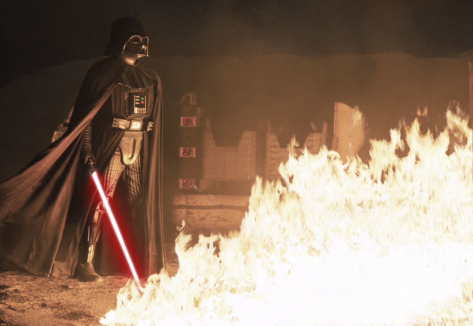 Darth Vader with his lightsaber standing over a fire